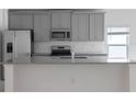Modern kitchen with gray cabinets, granite countertops, stainless steel appliances, and stylish tile backsplash at 4054 Serene Water Ave, Eustis, FL 32736