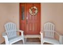 Warm and welcoming front door with a decorative wreath, flanked by two comfortable chairs at 4223 Arlington Ridge Blvd, Leesburg, FL 34748