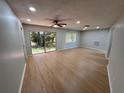 Spacious living room with wood-look flooring, ceiling fan, and sliding glass doors to the outside at 2308 Lake Helen Osteen Rd, Deltona, FL 32738