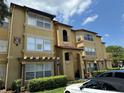 Three-story apartment complex with tan exterior and covered parking spaces at 5132 Conroy Rd # 937, Orlando, FL 32811