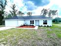 Freshly painted house exhibits neat landscaping with mulched garden beds, complemented by a concrete driveway and a front-facing garage at 2 Fisher Lane Way, Ocklawaha, FL 32179