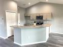 Bright kitchen showcases granite countertops, a breakfast bar with seating, stainless steel appliances, and wood-style flooring at 2 Fisher Lane Way, Ocklawaha, FL 32179