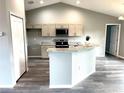 Open kitchen features granite countertops, stainless steel appliances, and an island bar with modern cabinetry and wood flooring at 2 Fisher Lane Way, Ocklawaha, FL 32179