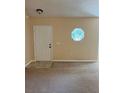 Living room with tan walls, carpet, and an octagonal window near the entry door at 1124 Chateau Cir, Minneola, FL 34715