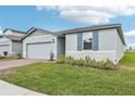 New home exterior featuring a garage, side yard, and brick driveway at 1489 Sea Glass Rd, Haines City, FL 33844