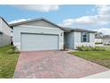 New home exterior featuring a brick driveway, garage and manicured lawn at 1489 Sea Glass Rd, Haines City, FL 33844