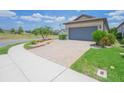 Paver driveway leading to a two-car garage, complemented by tidy landscaping and lush green grass at 745 Asturias Rd, Davenport, FL 33837