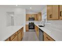 Well lit kitchen with stainless steel appliances, white countertops, and wood-grain cabinets at 8377 Wilder Pines Ave, Lakeland, FL 33809