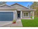 Close up of a single Gathering home showing the front door, garage door, and green lawn at 95 Malauka Place Trak, Ocklawaha, FL 32179