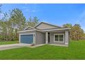 Single Gathering home boasts a blue garage door, green lawn, and freshly painted exterior at 95 Malauka Place Trak, Ocklawaha, FL 32179
