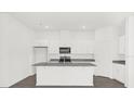 Kitchen island with granite countertop, stainless steel sink, and white cabinets at 8566 Caribbean Pine Way, Lakeland, FL 33809