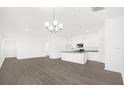 Open-concept living room and kitchen with hardwood floors and modern chandelier at 8566 Caribbean Pine Way, Lakeland, FL 33809