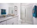 Bathroom featuring granite counters, framed mirrors, modern fixtures, a walk-in shower, a tiled floor, and modern decorations at 1559 Gardiner St, Haines City, FL 33844