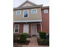 Townhome entrance with a walkway, landscaping, and a light beige and red exterior at 7532 Sunville Ave, Kissimmee, FL 34747