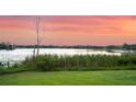 Scenic lake view with calm water, tall grass, and a beautiful sunset at 1700 Lake Markham Rd, Sanford, FL 32771