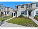 Inviting two-story townhome with neat landscaping and a walkway leading to the front door on a sunny day at 3229 Douglas Fir Dr, Apopka, FL 32703