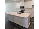 Bright kitchen features a center island, stainless appliances, white cabinetry, and wood flooring at 2608 Kinsale Ln, Ormond Beach, FL 32174