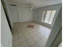 Open living room features neutral tile flooring, ceiling fan, two windows, and two doors at 821 Savona Pl, Kissimmee, FL 34758