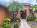 Inviting front entrance with brick walkway, palm tree, and lush landscaping at 681 Coronado Dr, Kissimmee, FL 34759