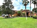 Beautiful lawn and mature trees surrounding a cozy home with a terracotta roof at 681 Coronado Dr, Kissimmee, FL 34759