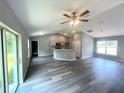 Spacious living room with vaulted ceiling, modern gray flooring, open to a sleek kitchen and ample natural light at 161 Fisher Crse, Ocklawaha, FL 32179