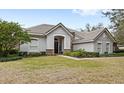 Gray stucco house with tile roof, stone accents, and lush landscaping; inviting front entrance at 25515 Hawks Run Ln, Sorrento, FL 32776