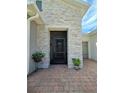 Inviting front entrance with stone accents, brick pathway, and potted plants at 840 Jasmine Creek Rd, Kissimmee, FL 34759