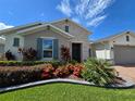 Well-manicured front yard featuring vibrant landscaping, lush lawn, and a charming home exterior with decorative shutters at 840 Jasmine Creek Rd, Kissimmee, FL 34759