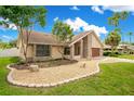 Beautifully landscaped front yard with decorative rock, a brick border, and mature trees enhancing the curb appeal of the home at 1121 Trotwood Blvd, Winter Springs, FL 32708