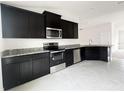 Modern kitchen with dark cabinets, granite countertops, and stainless steel appliances at 4376 Sagefield Dr, Harmony, FL 34773