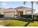Tan house with brown trim, a double-door entry, and a neatly landscaped lawn at 313 Kensington Dr, Davenport, FL 33897