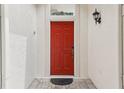 Inviting red front door with ornate hardware and a decorative transom window at 475 Windsor Pl, Davenport, FL 33896