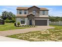 Two-story house with stone accents and a paved driveway at 233 Macaulay S Cv, Haines City, FL 33844