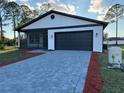 New home showcasing a stylish exterior with a dark garage door and screened-in porch at 1102 East Pkwy, Deland, FL 32724