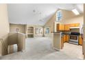 Bright, carpeted living room with vaulted ceilings adjacent to a kitchen with wooden cabinets at 3383 Westchester Square Blvd # 204, Orlando, FL 32835