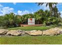 Community entrance sign surrounded by lush tropical foliage and palm trees on a sunny day at 5530 Metrowest Blvd # 9-211, Orlando, FL 32811