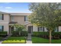 Charming townhome exterior with manicured landscaping, lush green grass, and a welcoming front entrance, nestled beneath a tree at 1625 Reflection Cv, Saint Cloud, FL 34771