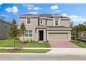 Two-story home featuring a tan exterior, two-car garage, a manicured lawn, and sidewalk at 1197 Happy Forest Loop, Deland, FL 32720