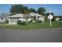 Single-story house with gray siding, attached garage, and a grassy yard on a corner lot at 20505 Queen Alexandra Dr, Leesburg, FL 34748