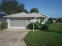 Ranch-style home with gray siding, double garage, and landscaped front yard at 20505 Queen Alexandra Dr, Leesburg, FL 34748
