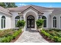 Close up of the entrance showcasing a beautiful walkway and an ornate door with flourishing plant life at 1306 Sweetwater Club Blvd, Longwood, FL 32779