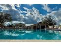 Community pool with clear blue water, lounge chairs, gazebo and clubhouse with blue sky and clouds reflected in the water at 4901 Pleasant Hollow Trl, Lakeland, FL 33811
