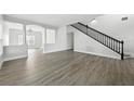 Open-concept living room with light gray wood floors and staircase with black railing at 724 Tahiti Dr, Kissimmee, FL 34758