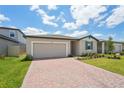 View of a single-story home featuring a brick driveway, garage, and lush lawn under a cloudy sky at 3824 Giorgio Dr, Winter Haven, FL 33884