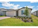 Landscaped front yard of a single-story home with a beige garage and blue window shutters at 3824 Giorgio Dr, Winter Haven, FL 33884