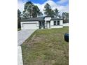 Newly built home with gray and white exterior, paved driveway, and grassy lawn at 6807 Sw 153Rd Place Rd # 6807, Ocala, FL 34473