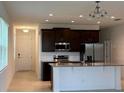 Open-concept kitchen boasts stainless steel appliances, dark wood cabinetry, and a breakfast bar at 1926 Church Lake St, Groveland, FL 34736