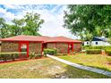 Inviting brick home with a red roof, lush green landscaping, and a concrete walkway leading to the front door at 1546 Stormway Ct, Apopka, FL 32712