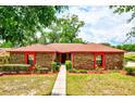 Charming single-story brick home featuring a well-kept lawn, vibrant landscaping, and a welcoming entryway at 1546 Stormway Ct, Apopka, FL 32712