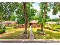 Charming single-story brick home with a well-manicured lawn, mature trees, and walkway to a red front door at 1546 Stormway Ct, Apopka, FL 32712